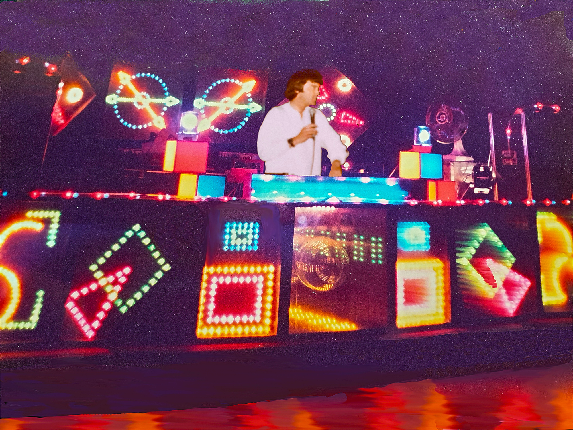 Nigel in the DJ booth surrounded by neon lighting