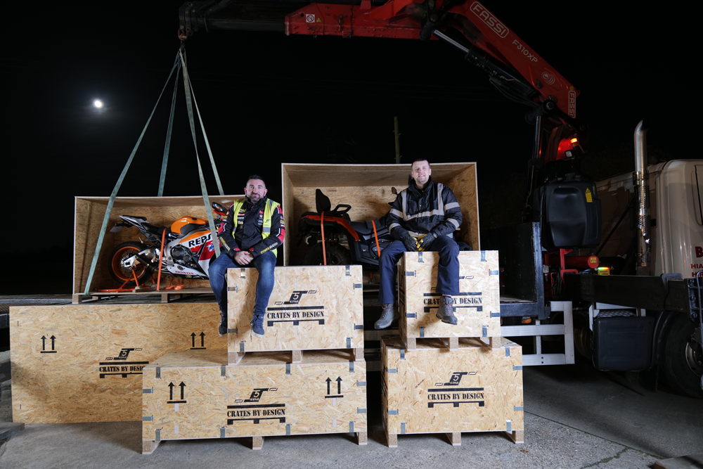 Staff members sitting on crates with motorcycles on display.