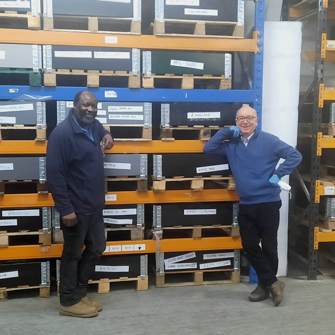 Noel and Roger leaning on some warehouse shelving