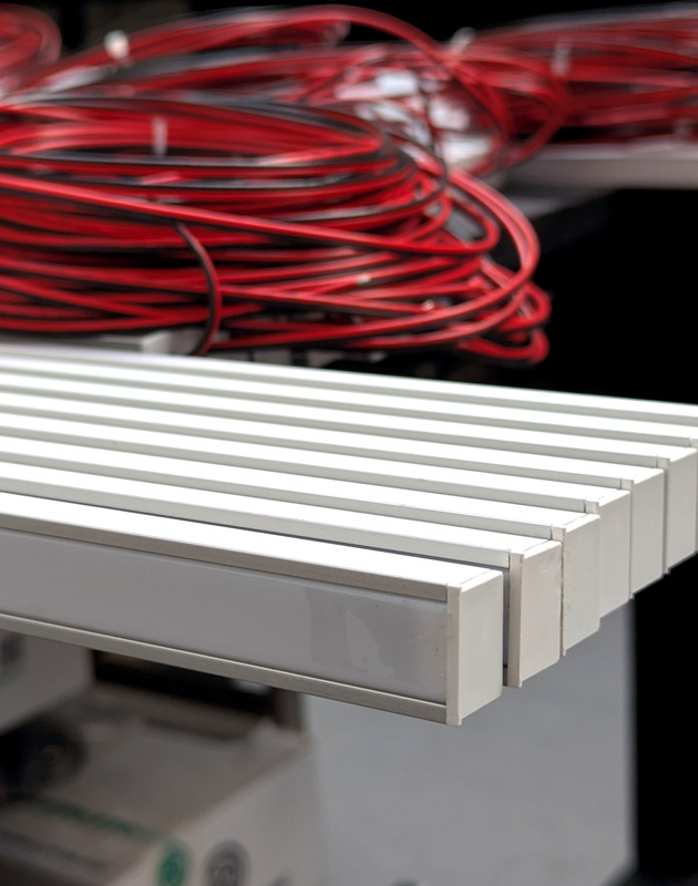 close up of assemled custom LED strip with covers with red and black cabling in the background