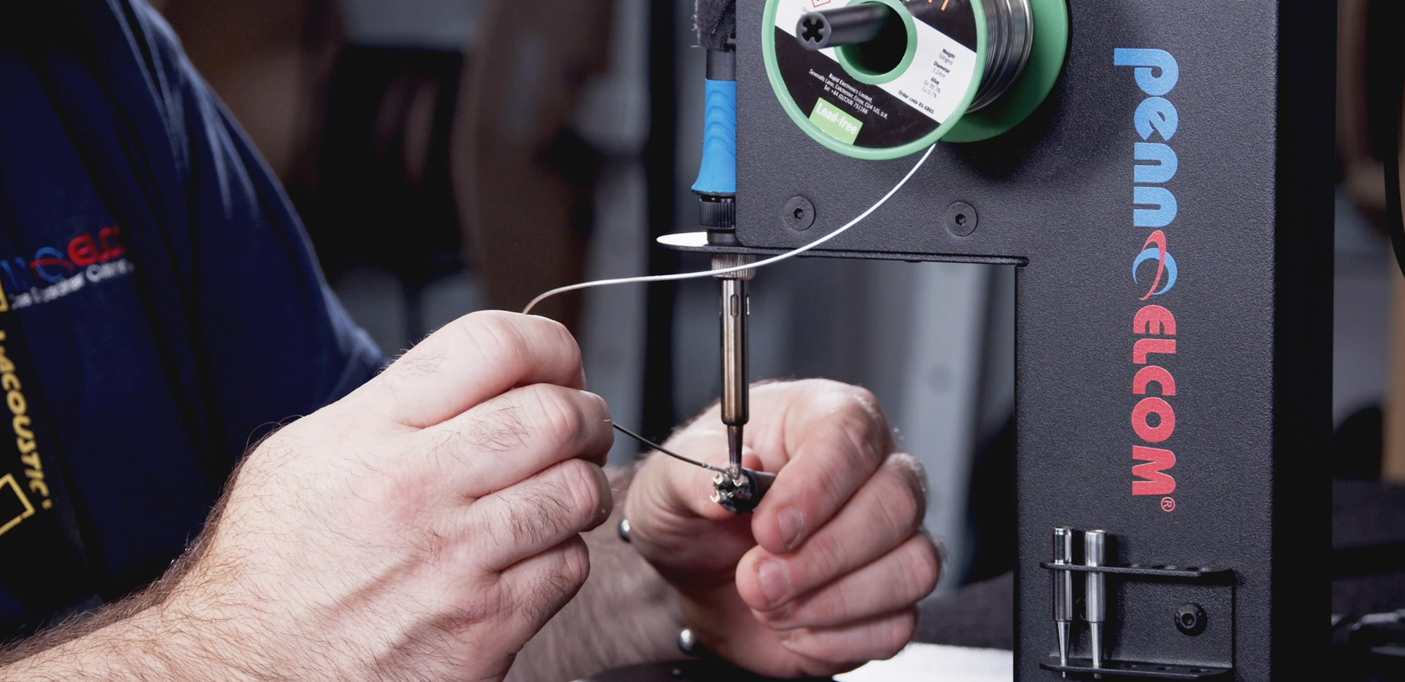 close up of man using soldering iron on connector using the SSLW solder iron stand from Penn Elcom
